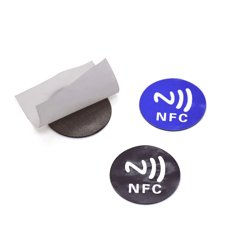 مجموعة من وسوم RFID الدائرية من PVC المخصصة للأسطح المعدنية باللونين الأزرق والأسود، مع ورقة فصل منزوعة تُظهر الطبقة الخلفية العازلة لتأثير المعدن والمخصصة للتثبيت الموثوق.