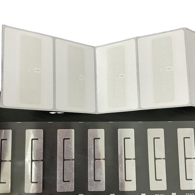 تُظهر هذه الصورة صفائح ملصقات RFID نهائية فوق شرائط بطانات مكشوفة لمقارنة الملصقات القابلة للطباعة وبنى الهوائيات.