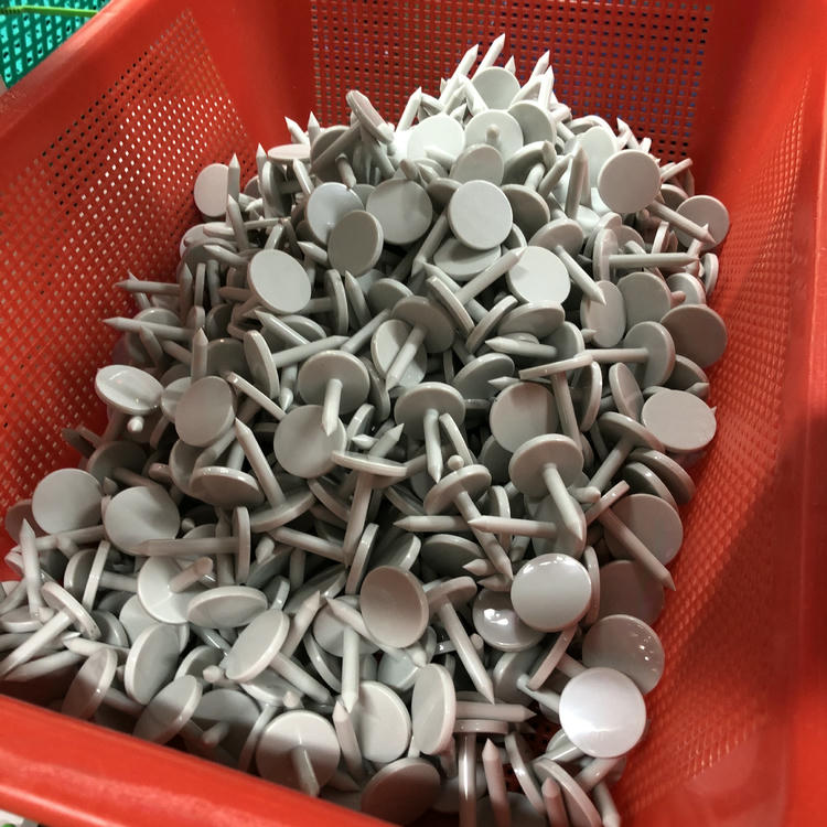 تُظهر الصورة سلة مملوءة بعلامات RFID مسمارية بيضاء من طراز NAIL06-6 أثناء الفرز أو التعبئة أو الفحص في المصنع.