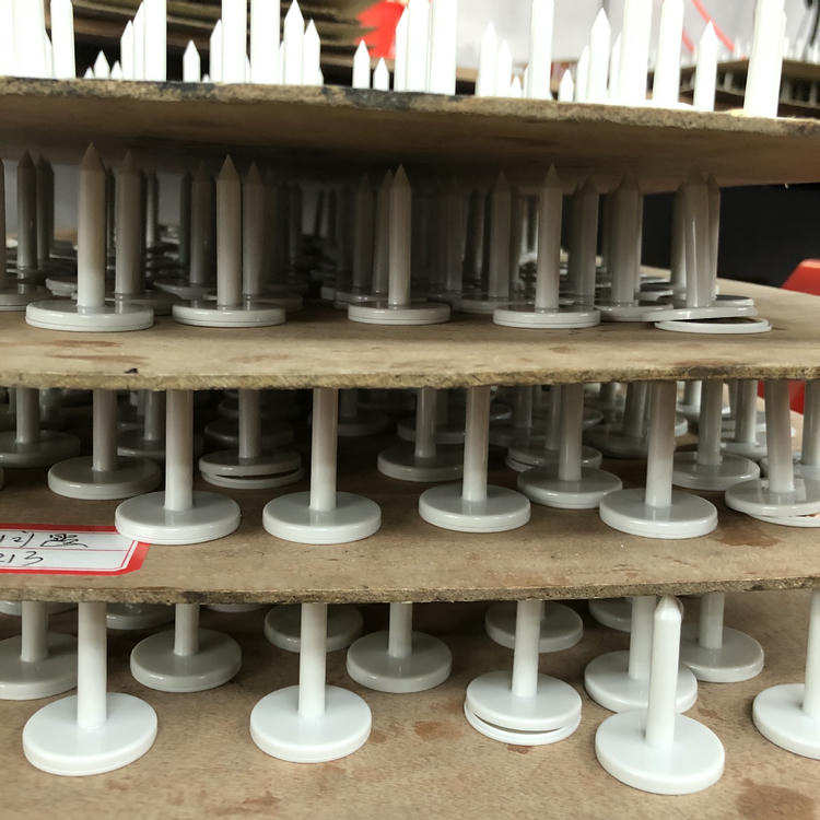 تُظهر الصورة عدة علامات RFID مسمارية بيضاء من طراز NAIL06-6 مرتبة على ألواح متعددة الطبقات أثناء الإنتاج أو التجفيف في المصنع.