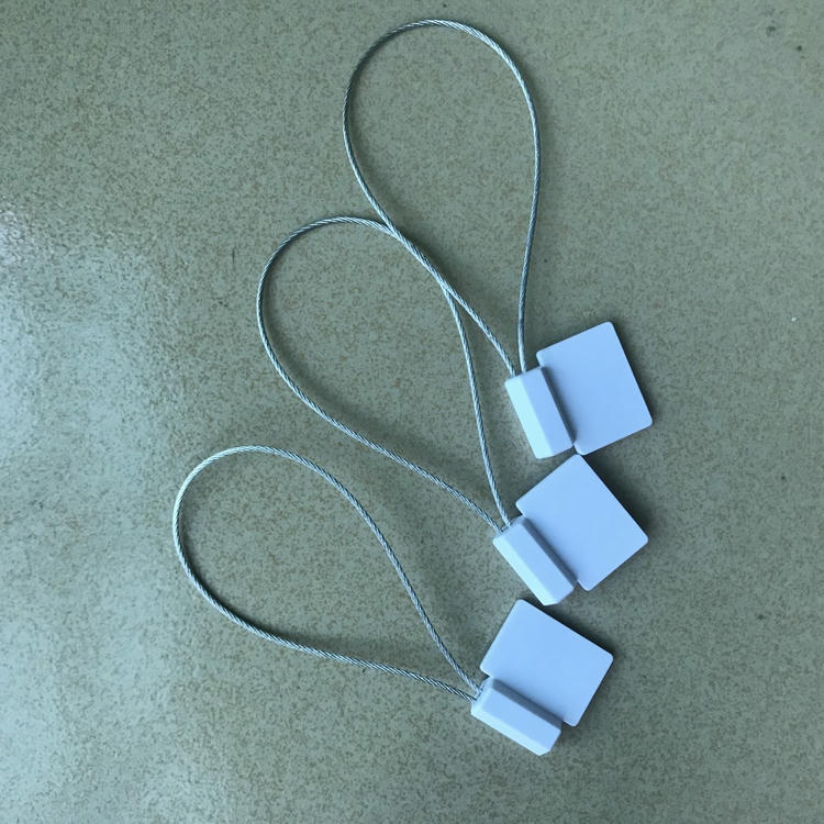 ثلاثة أختام RFID أمنية بيضاء SS3626-1 مرتبة بشكل قطري مع أسلاك فولاذية ملساء ملتفة على خلفية منسوجة.