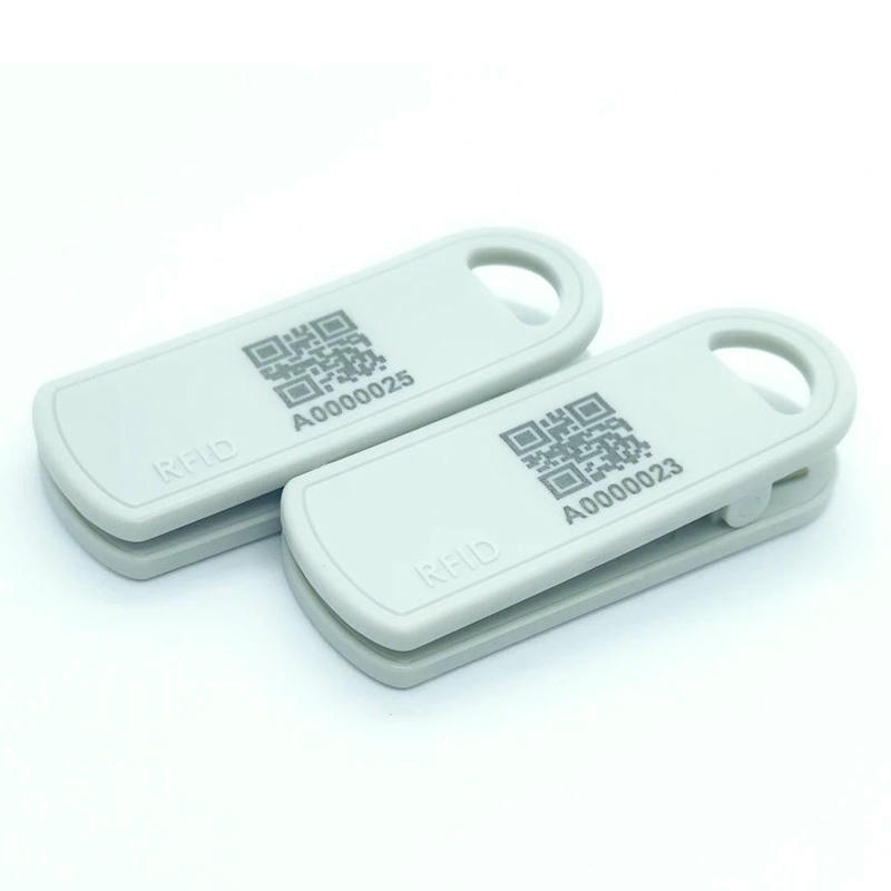 تُظهر هذه الصورة علامتي مشبك RFID بيضاوين SV-013 جنبًا إلى جنب، مع رمز QR لتعريف مخزون التجزئة.