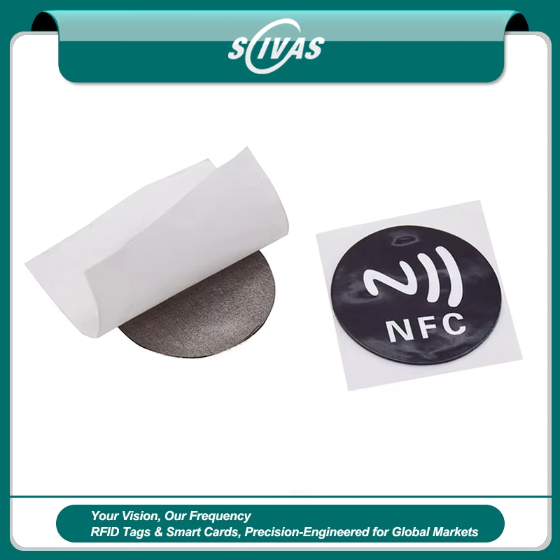صورة داخل إطار SCIVAS لوسم RFID دائري من PVC مخصص للأسطح المعدنية ومطبوع عليه NFC، بجوار ورقة الفصل وطبقة الفريت المخصصة لعزل تأثير المعدن عند التثبيت.